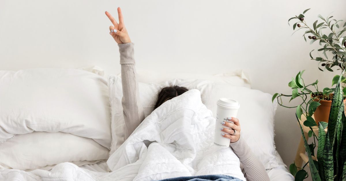 ragazza che dorme bene e fa segno di vittoria a letto