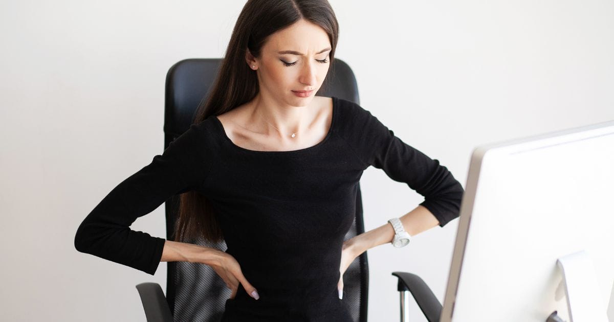 ragazza che soffre di stress che si tieni i fianchi in ufficio