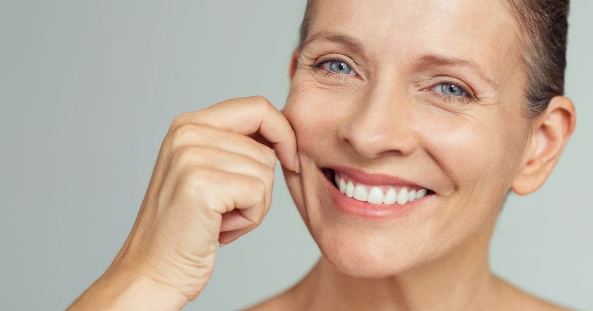 donna che si pizzica la pelle migliorata dopo l'assunzione di integratori di retinolo