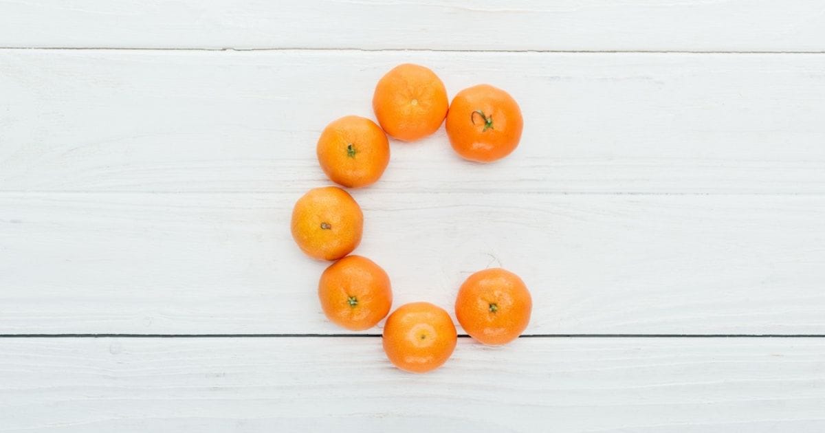 arance formano la lettera C su sfondo di legno a indicare la vitamina C
