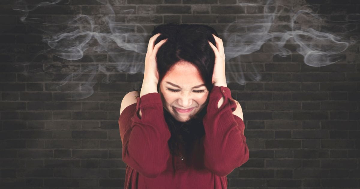 donna si tiene le mani tra i capelli con fumo disegnato sopra la testa