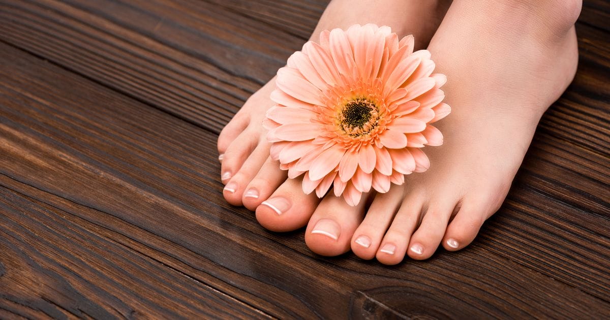 piedi con unghie sane e un fiore tra le dita