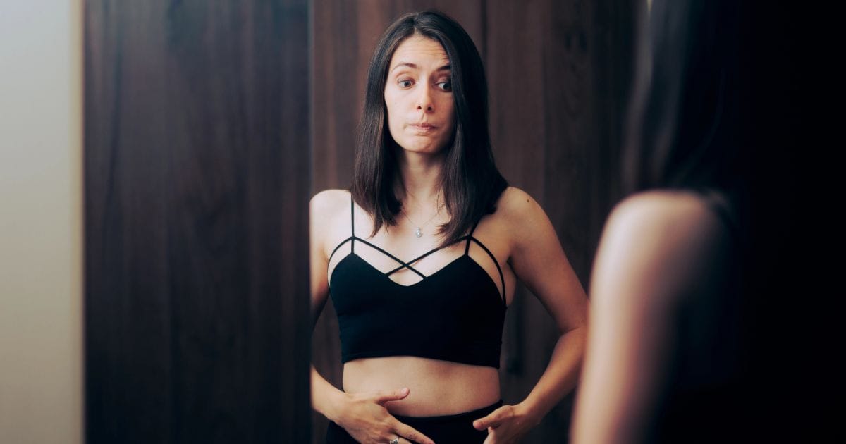 donna davanti allo specchio si chiede cosa fare per eliminare il gonfiore addominale