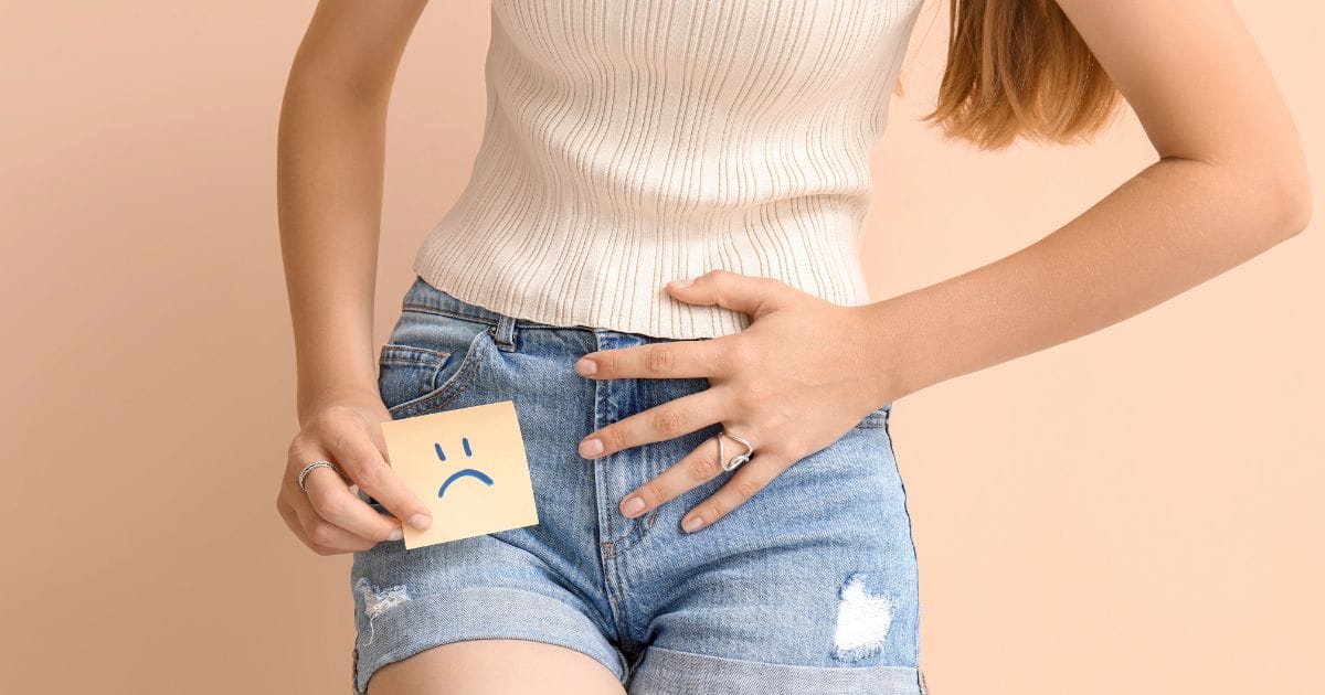 donna tiene cartellino con faccia triste disegnata a simboleggiare il dolore che si prova per la cistite