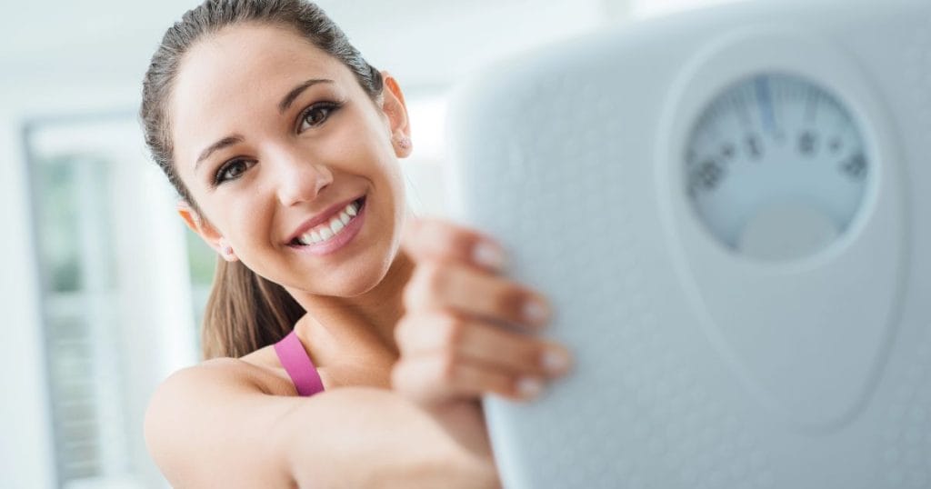 donna felice con bilancia dopo avere assunto gli integratori alimentari per ingrassare