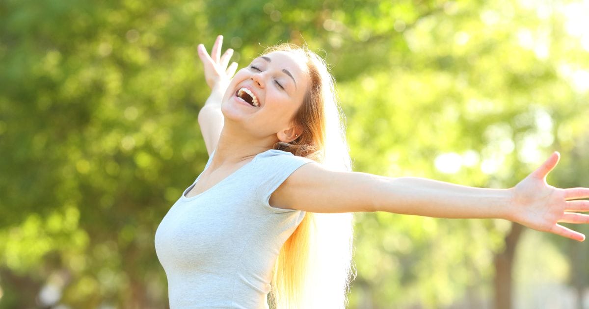 donna felice allarga le braccia in un parco